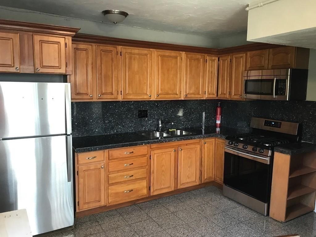 a kitchen with stainless steel appliances granite countertop a refrigerator stove top oven