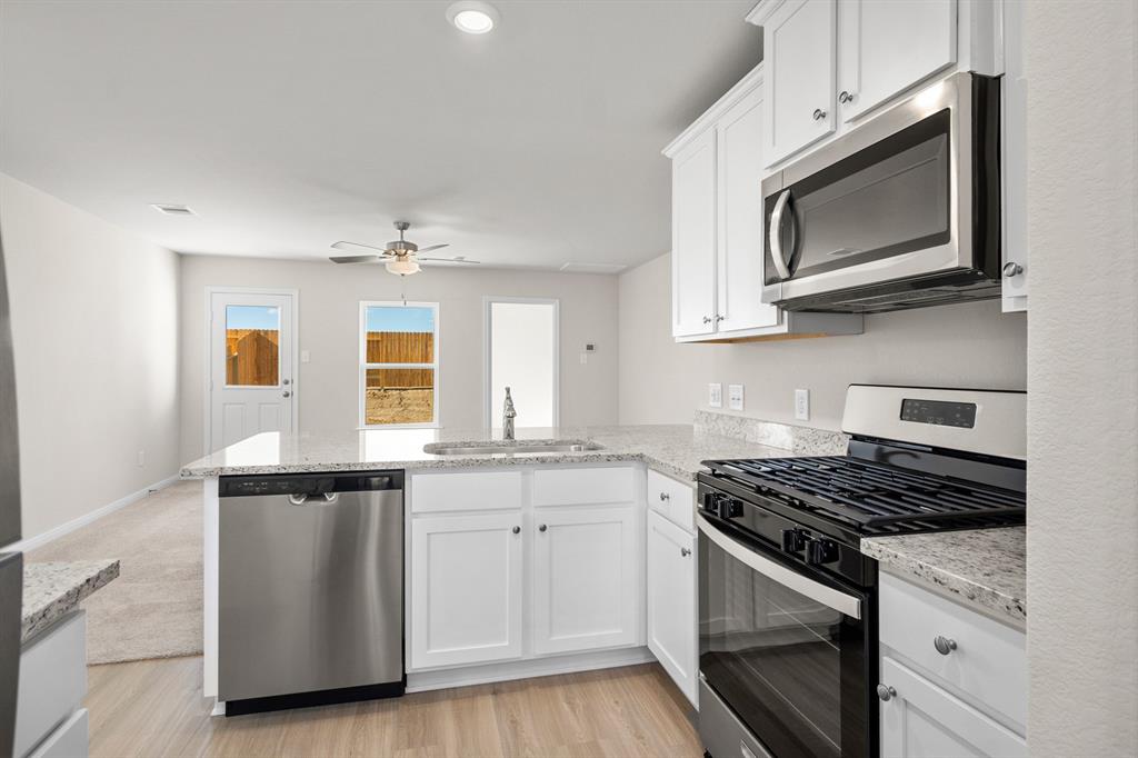 a kitchen with stainless steel appliances granite countertop a stove a sink and a microwave