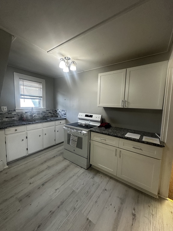 a kitchen with granite countertop a sink cabinets and wooden floor