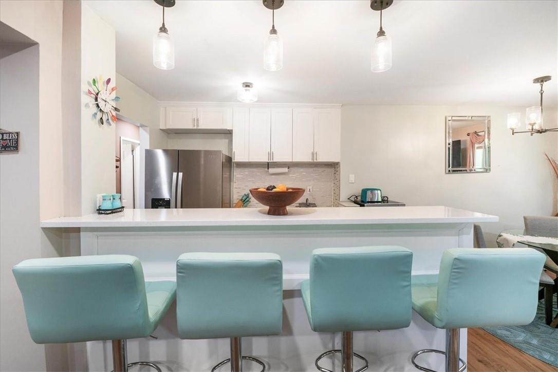 a kitchen with stainless steel appliances granite countertop a table chairs and a refrigerator