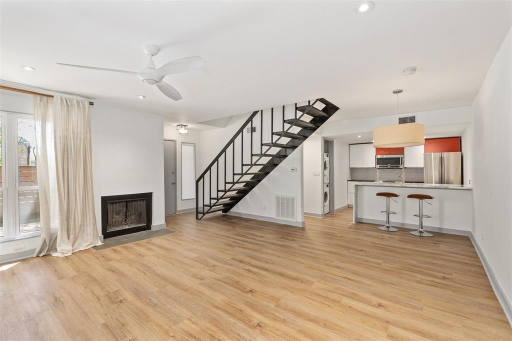 a view of an empty room with wooden floor fireplace and windows