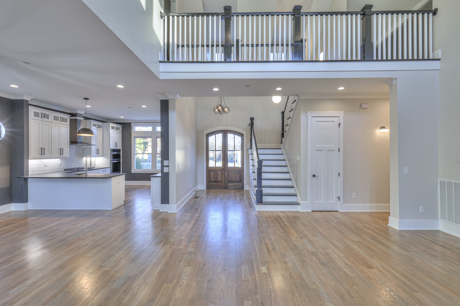 a view of a hallway with wooden floor and a kitchen