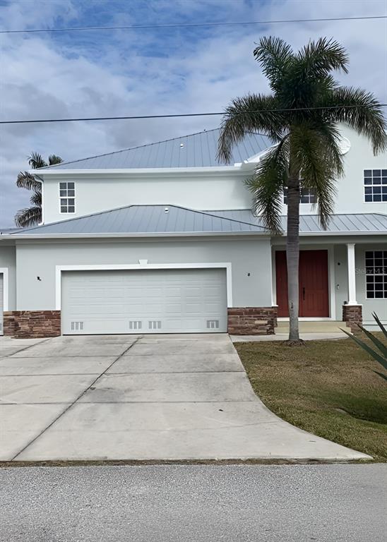 a front view of a house with garage and plants