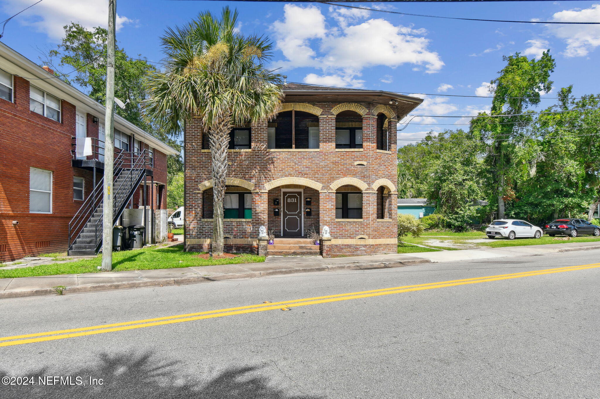 a view of a brick house with a yard and large tree