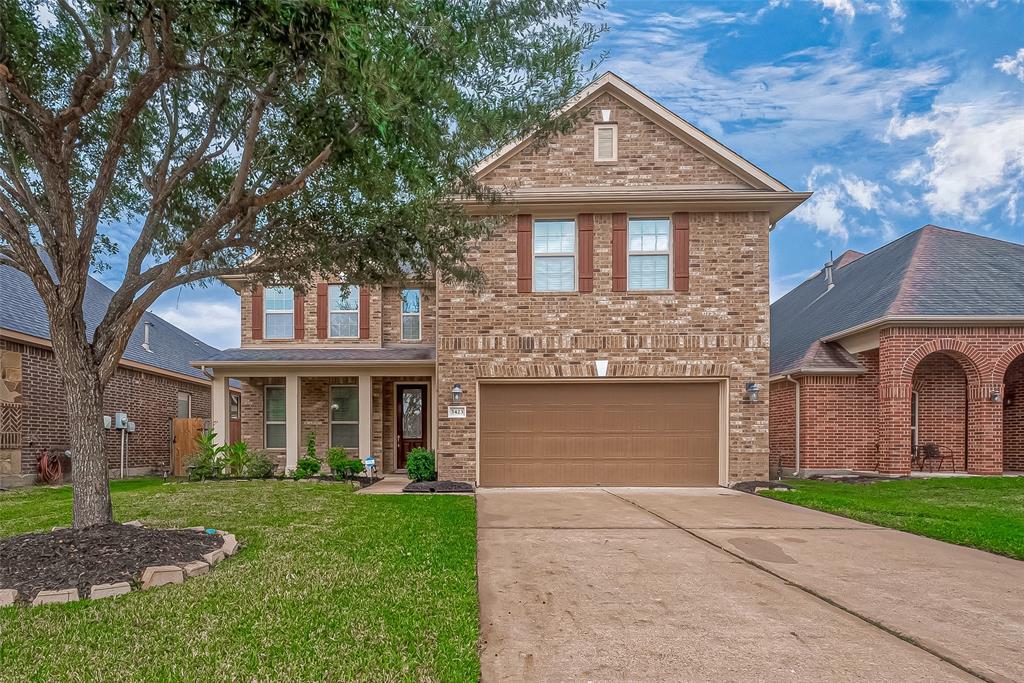 Welcome Home! Stunning curb appeal! A two-story brick home with a well-manicured lawn, a mature tree in the front yard, and an attached two-car garage.