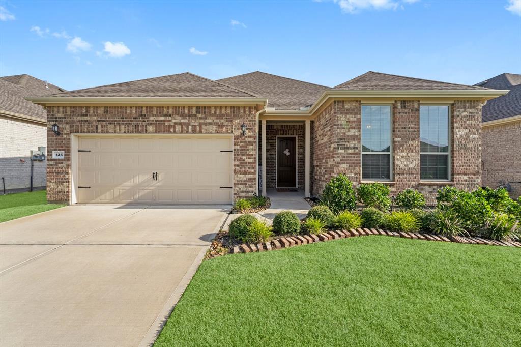 This is a single-story brick home featuring a two-car garage, neatly landscaped front yard, and a welcoming entryway.