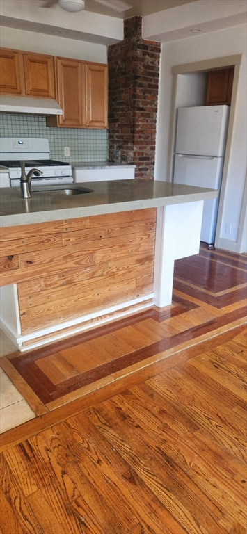 a view of a kitchen with kitchen island a sink wooden floor and a counter top space