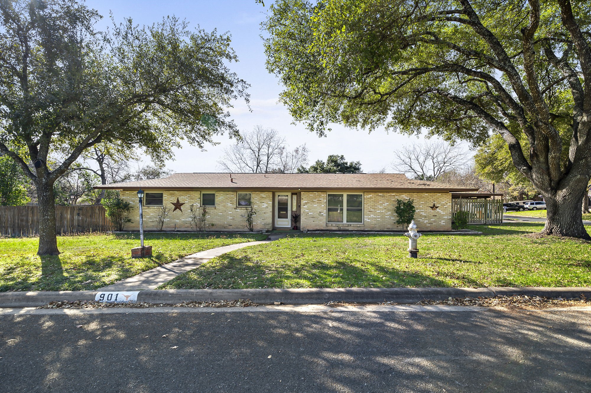 a view of a house next to a yard with road and trees