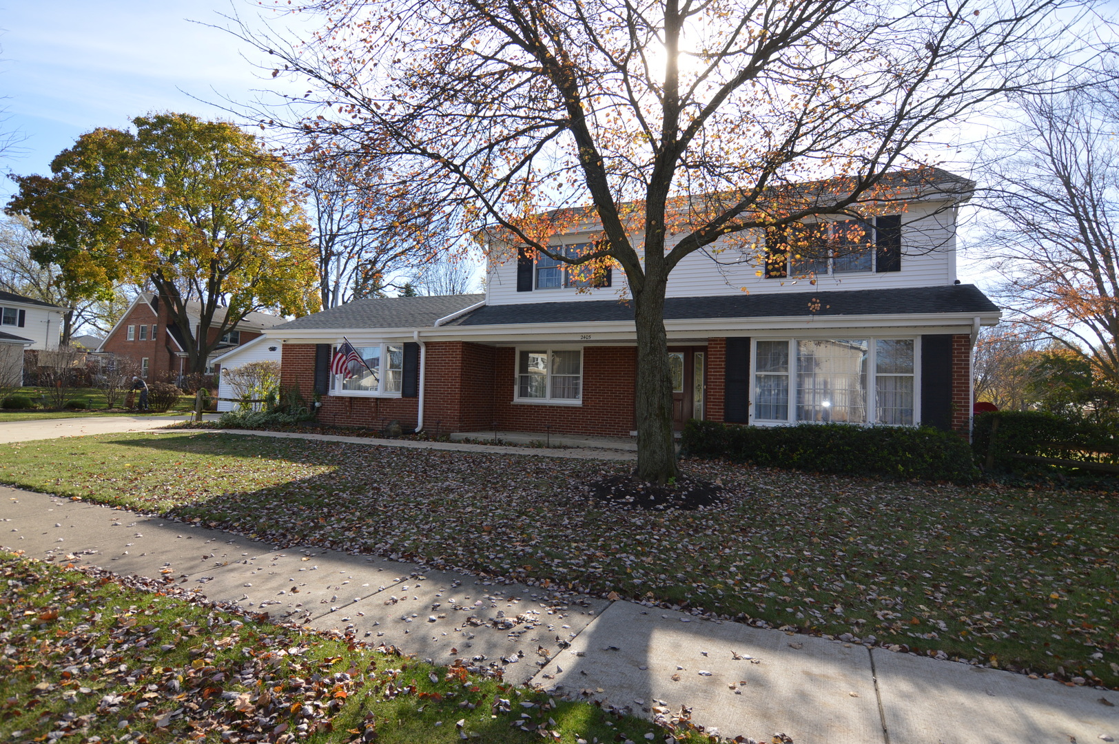 a view of a brick house next to a yard with large trees