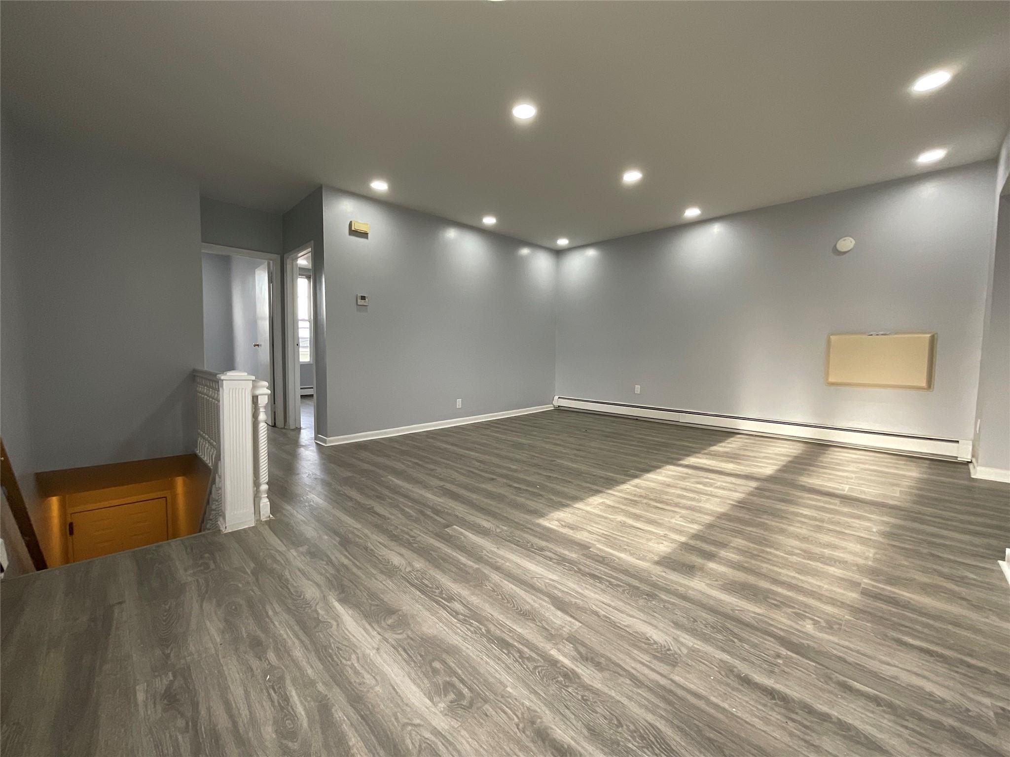 Unfurnished room with dark hardwood / wood-style floors and a baseboard heating unit