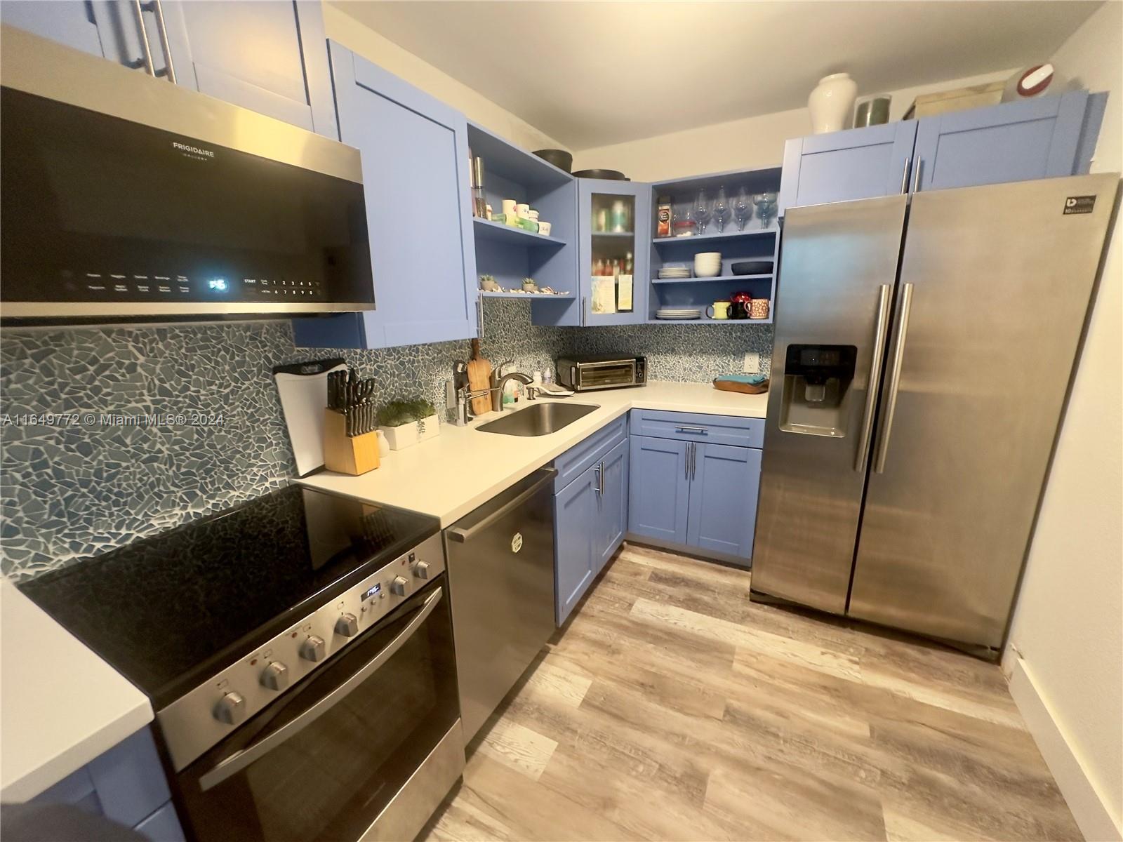 a kitchen with stainless steel appliances granite countertop a refrigerator a stove and a sink with wooden cabinets