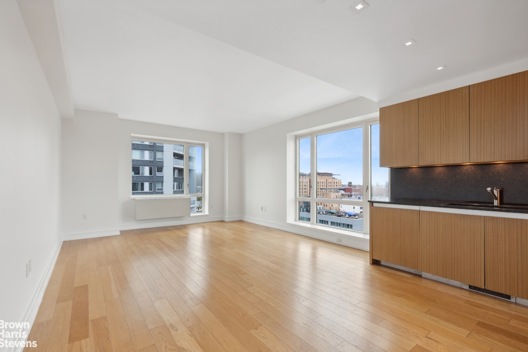 a living room with stainless steel appliances wooden floors and kitchen view