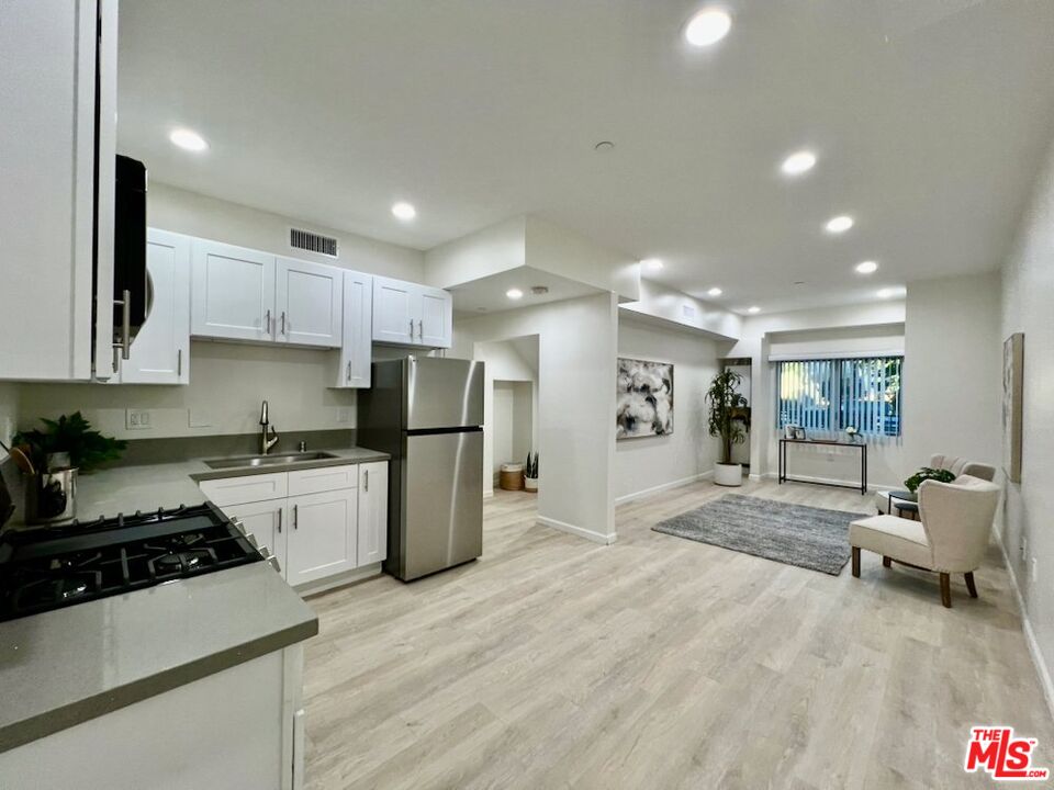 a large white kitchen with stainless steel appliances granite countertop a stove and a sink