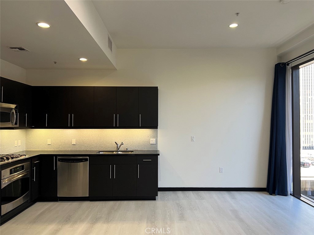 a view of kitchen with stainless steel appliances granite countertop a stove and a sink