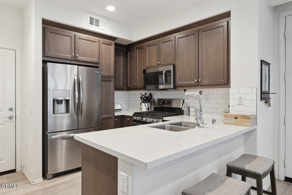 a kitchen with a refrigerator a microwave a sink and cabinets