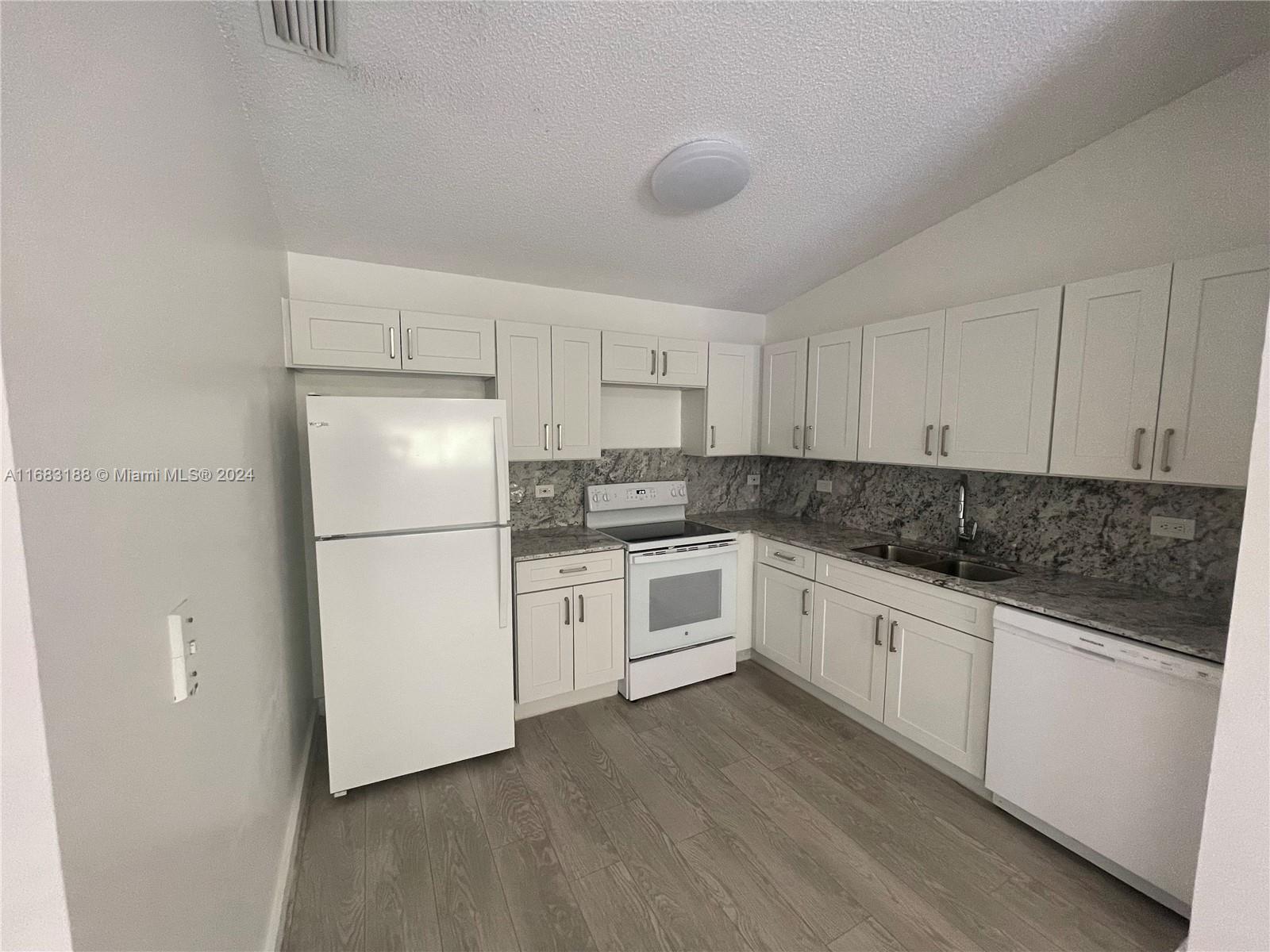 a kitchen with granite countertop white cabinets and white appliances