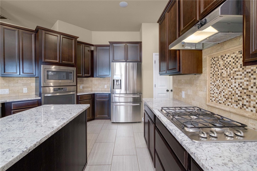 a kitchen with granite countertop a stove sink and refrigerator