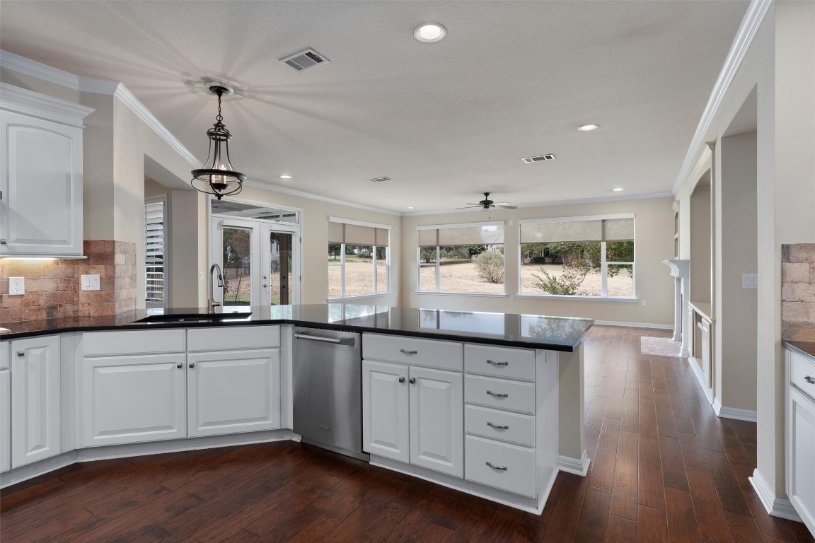 a large kitchen with granite countertop a large window and white cabinets