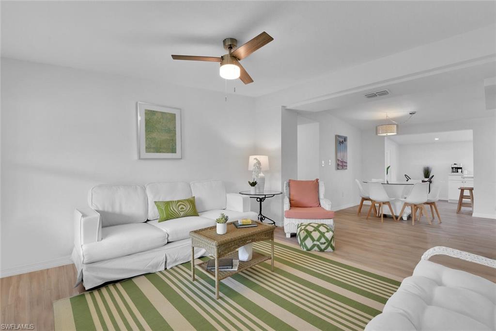 a living room with furniture and a dining table with wooden floor