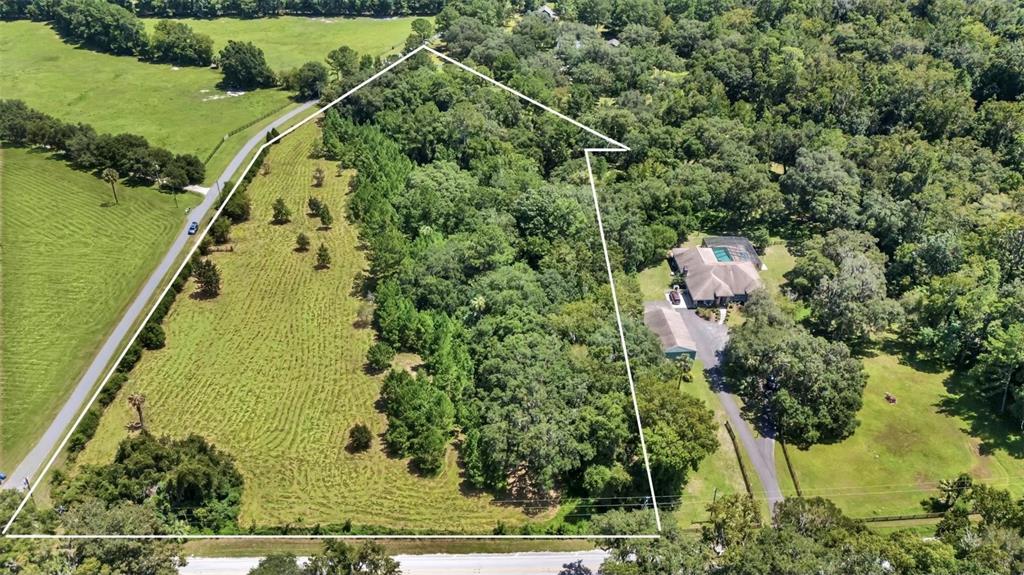 an aerial view of residential house with outdoor space and trees all around