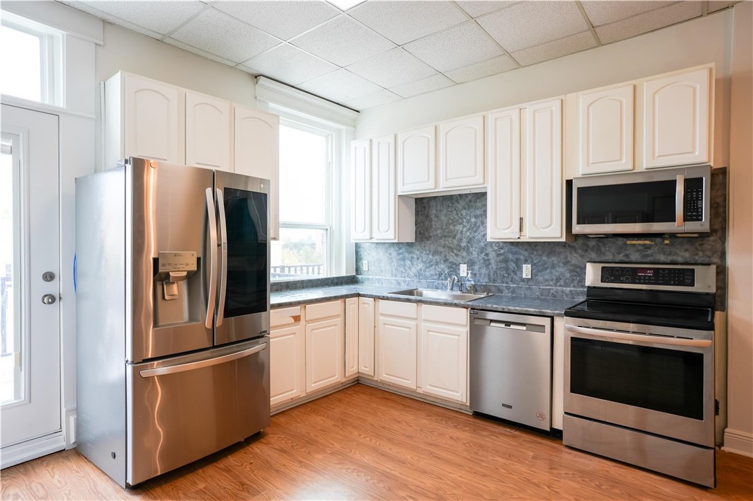 Kitchen with a paneled ceiling, sink, light hardwo