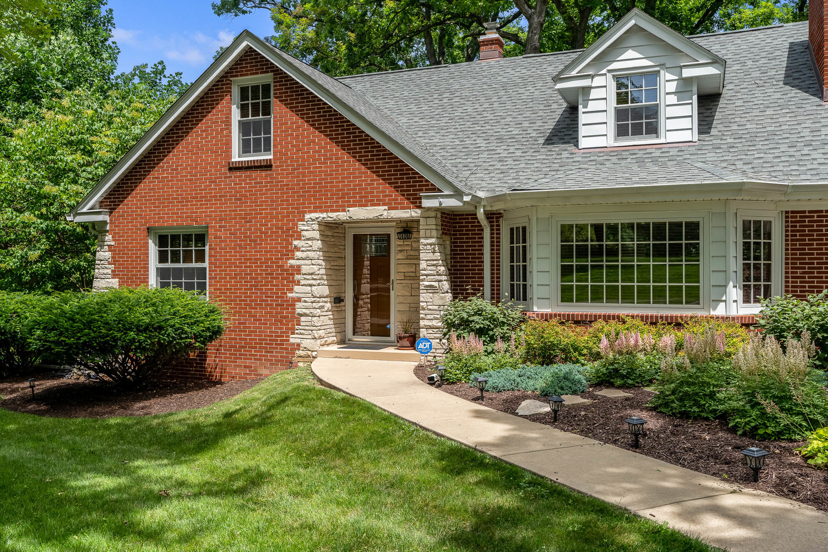 a front view of a house with a garden and plants