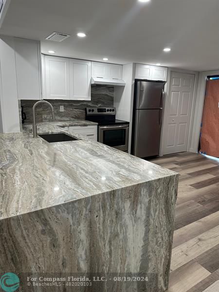 a large kitchen with kitchen island a sink stainless steel appliances and cabinets