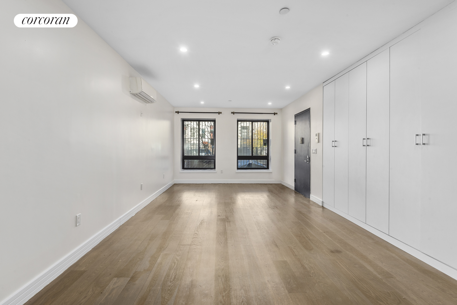 a view of an empty room with a window and wooden floor