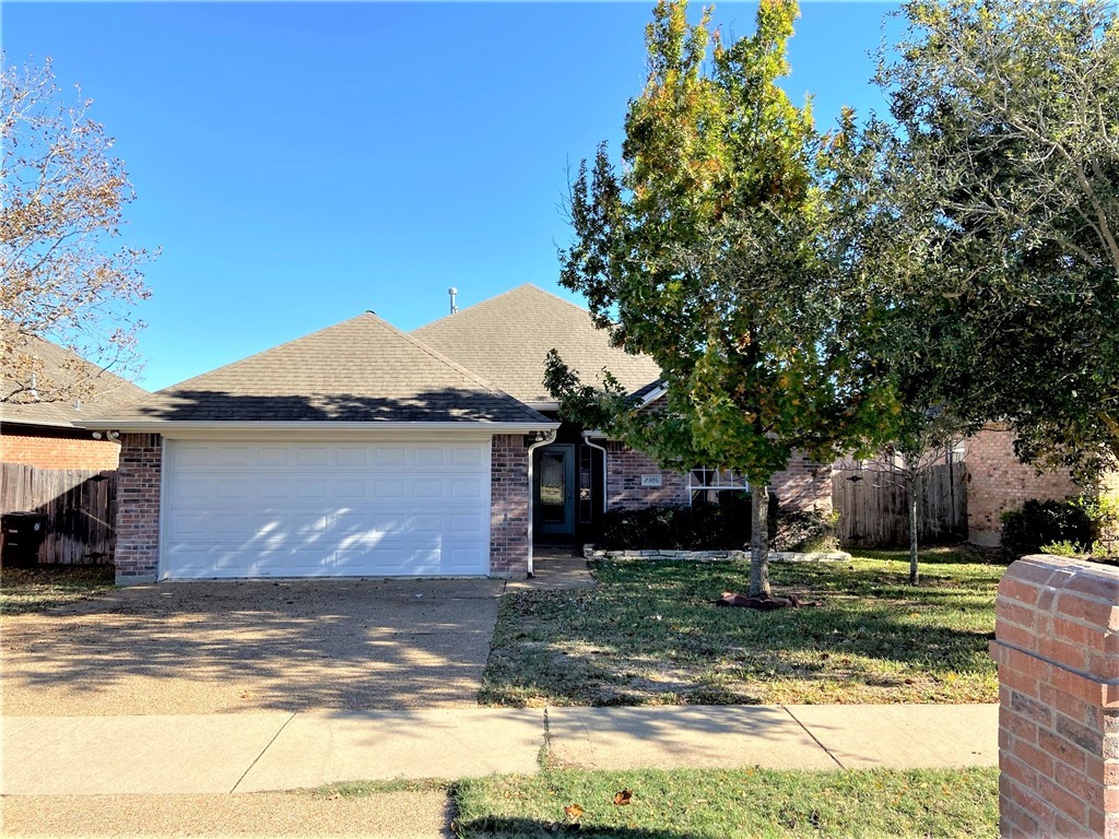 View of front of home with a front yard and a gara