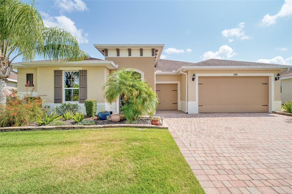 a front view of a house with a yard and potted plants