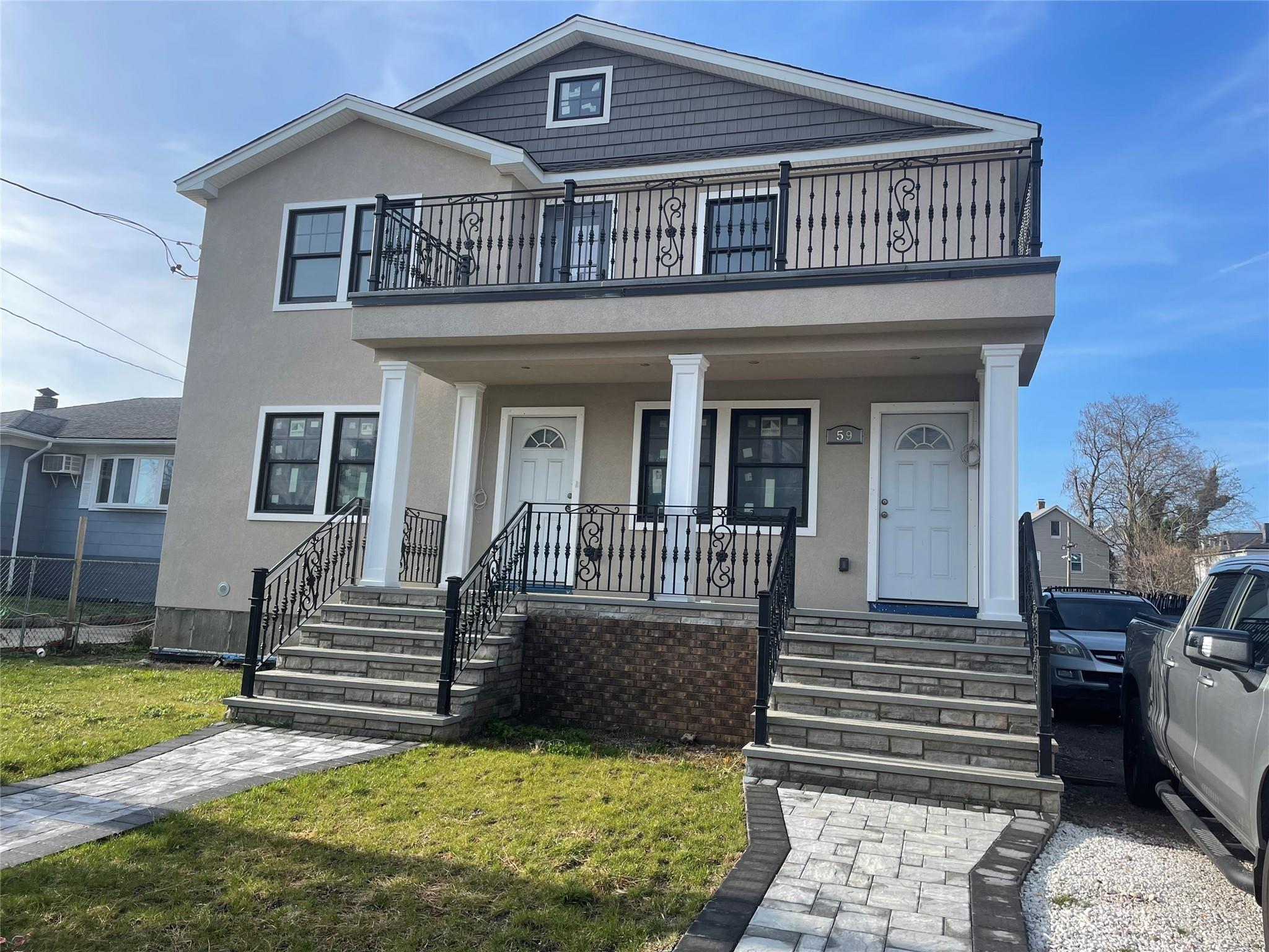 View of front facade featuring a balcony, covered porch, and a front yard