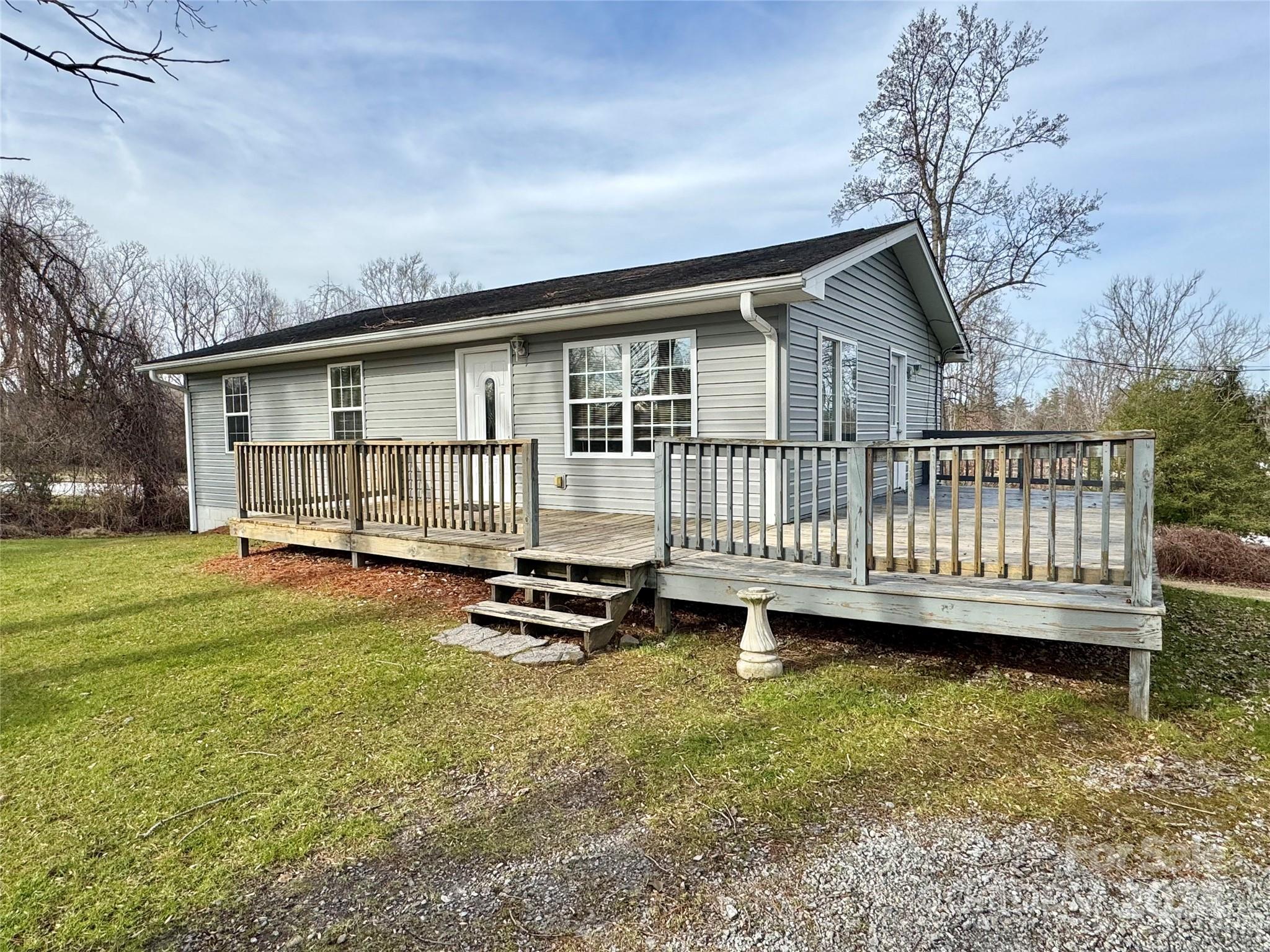 a view of a house with a wooden deck and a yard