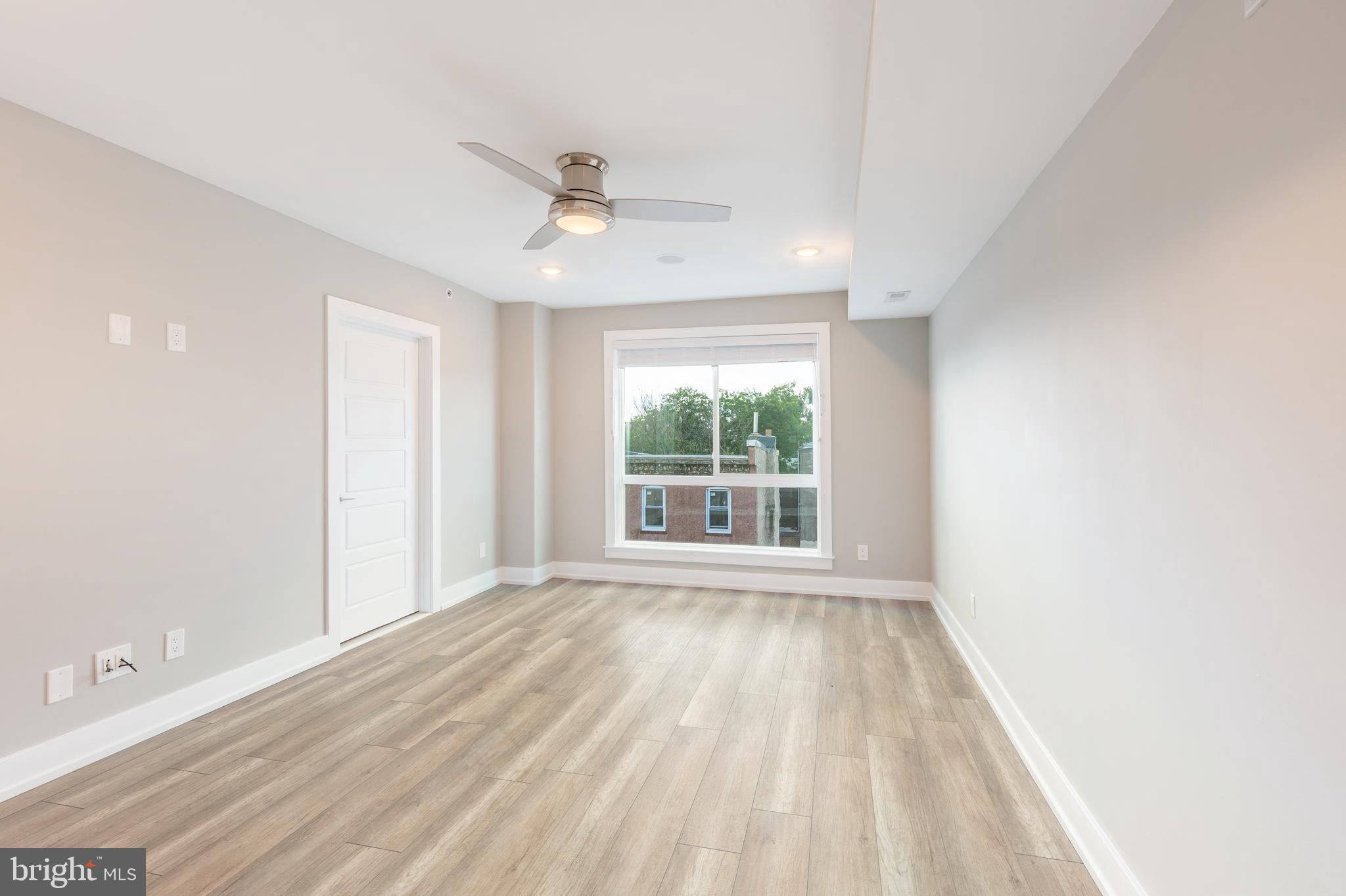 a view of an empty room with a window and wooden floor