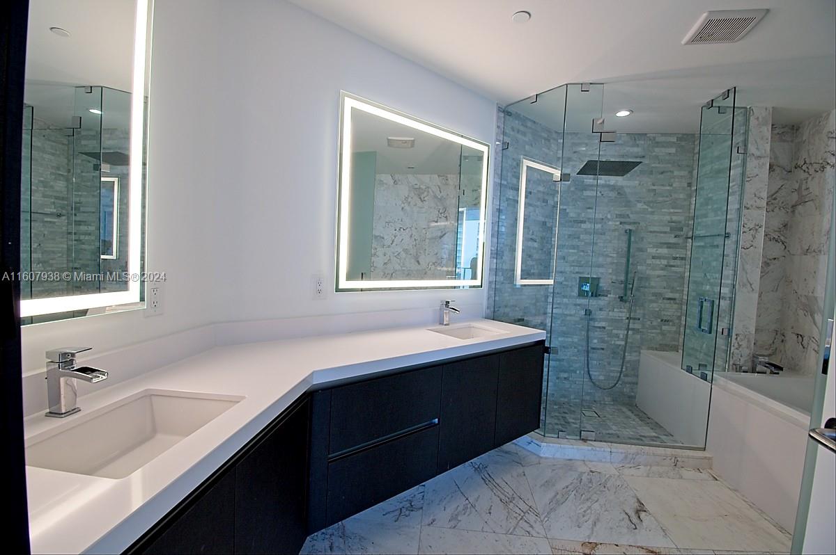 a bathroom with a tub sink shower and mirror