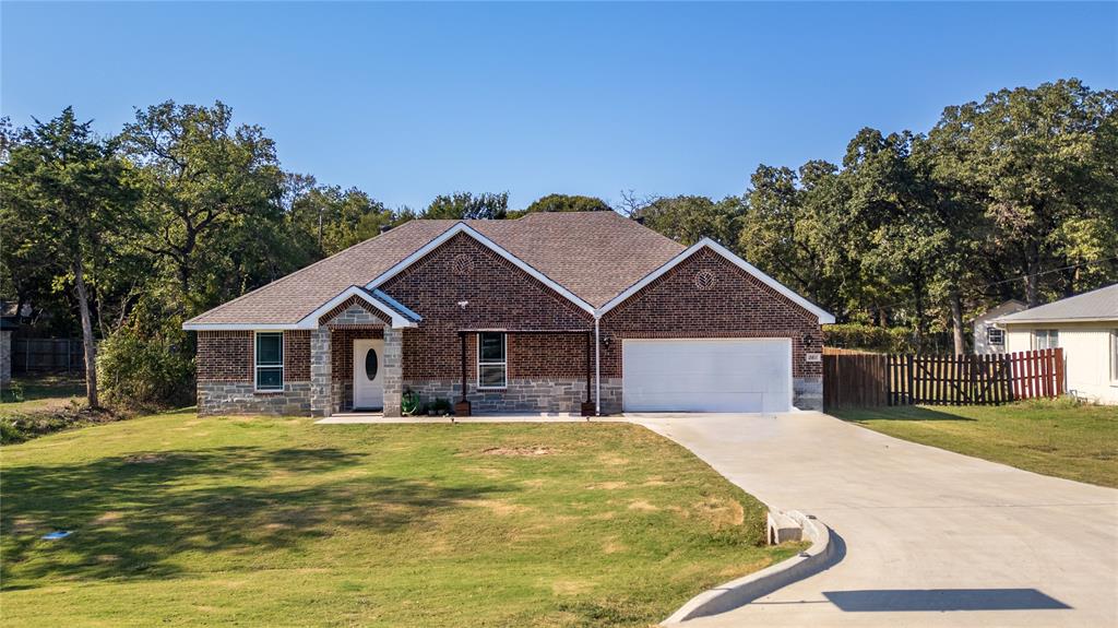 a front view of house with yard and trees in the background