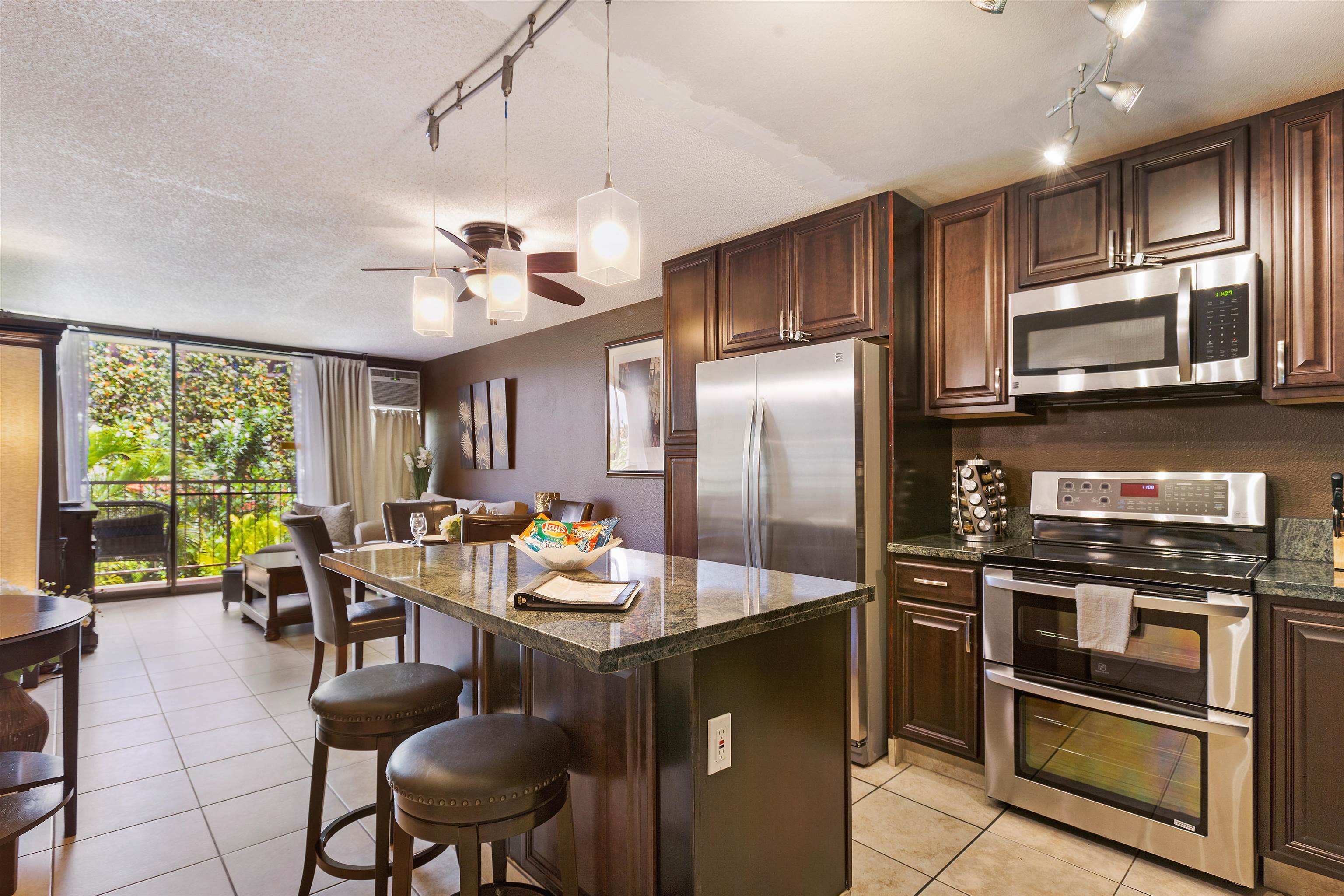 a kitchen with stainless steel appliances granite countertop a stove refrigerator sink dining table and chairs