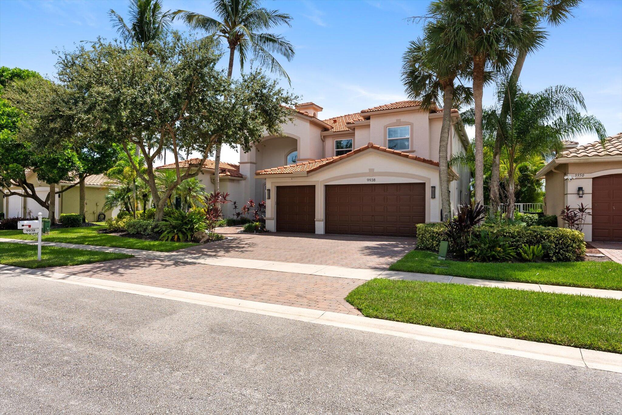 a front view of a house with a garden and palm trees