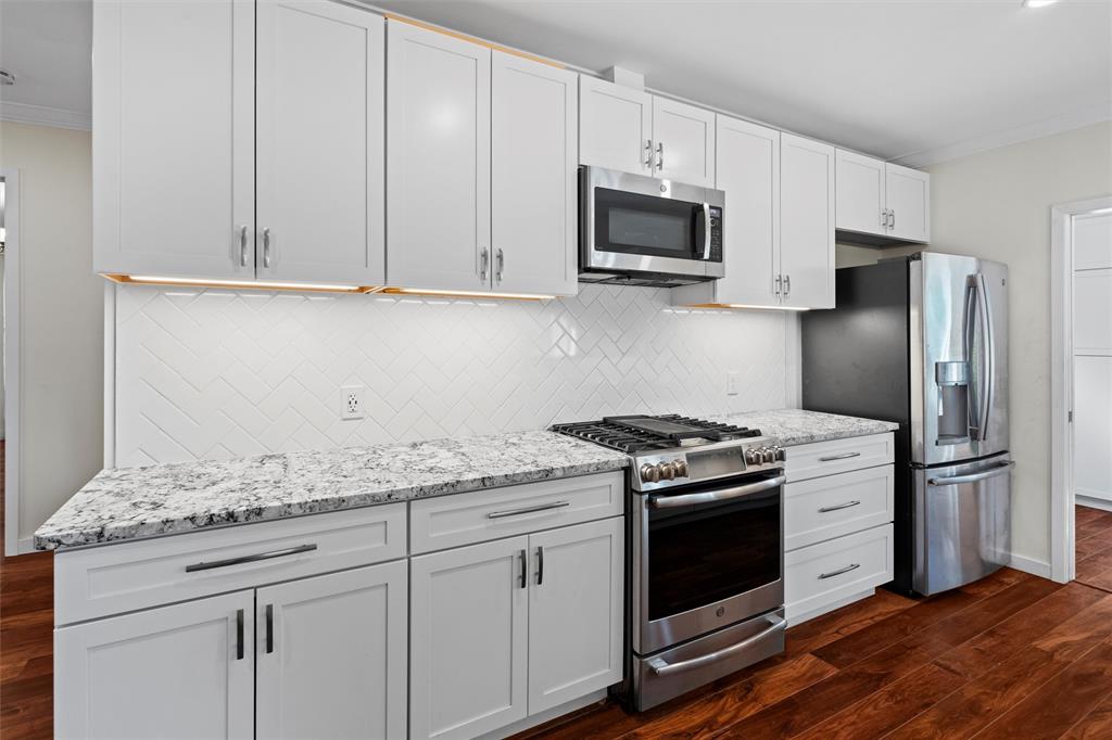 a kitchen with granite countertop white cabinets and stainless steel appliances