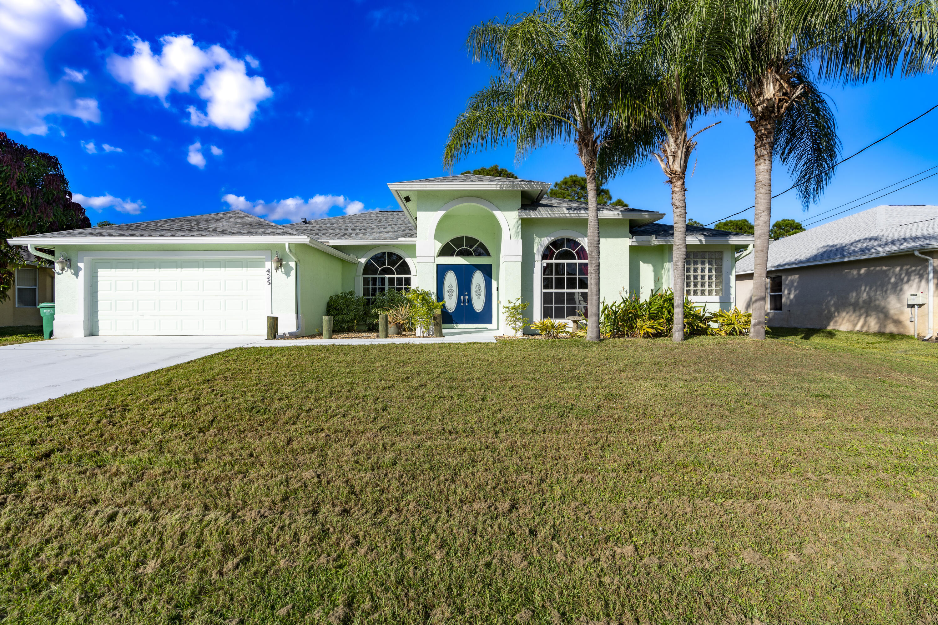 a view of a house with a yard and palm trees