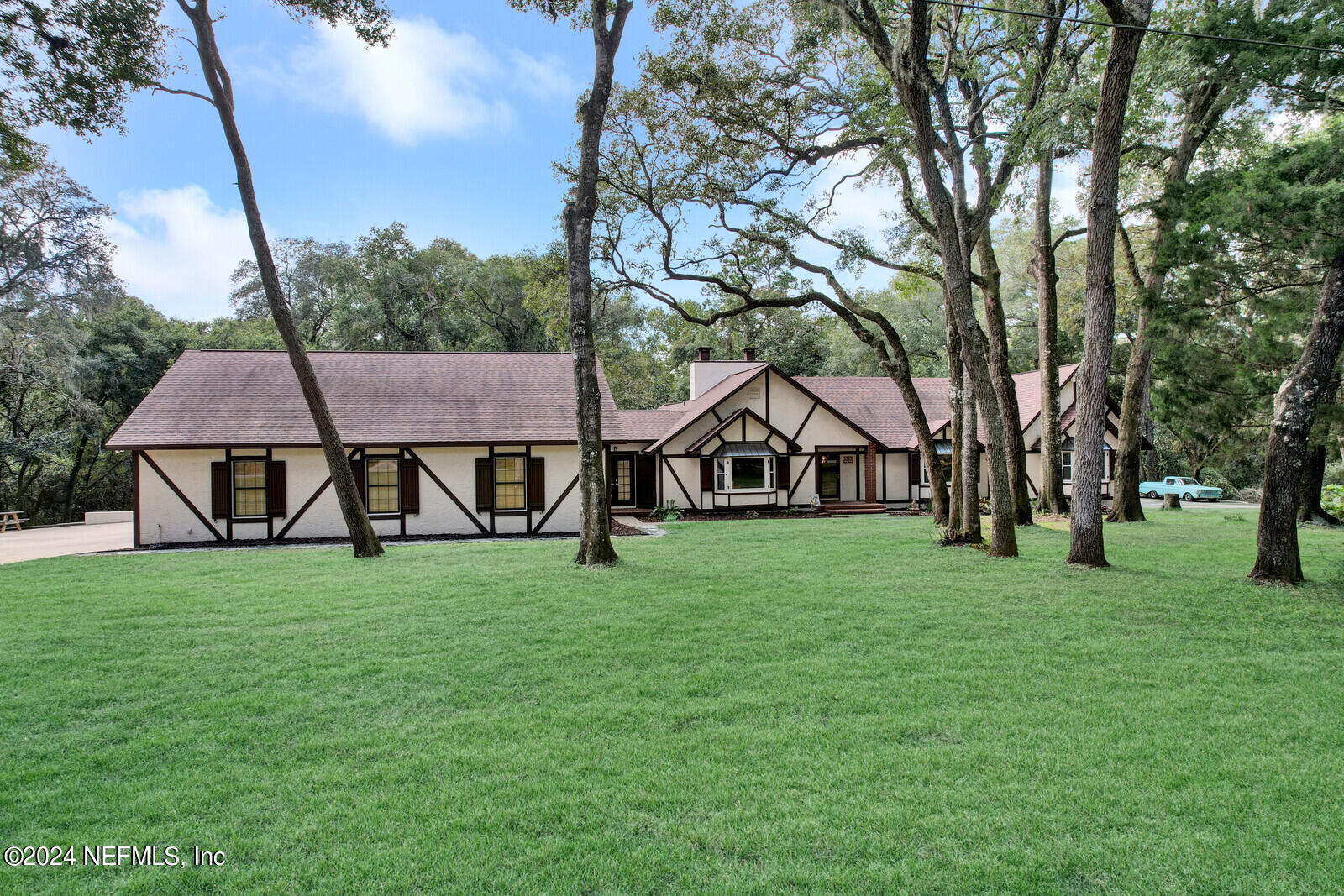 a view of a house next to a big yard with large trees