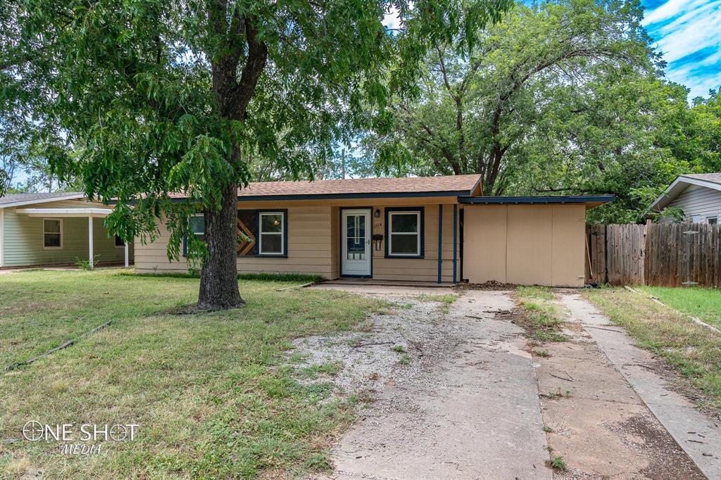 a view of a house with a yard and large tree