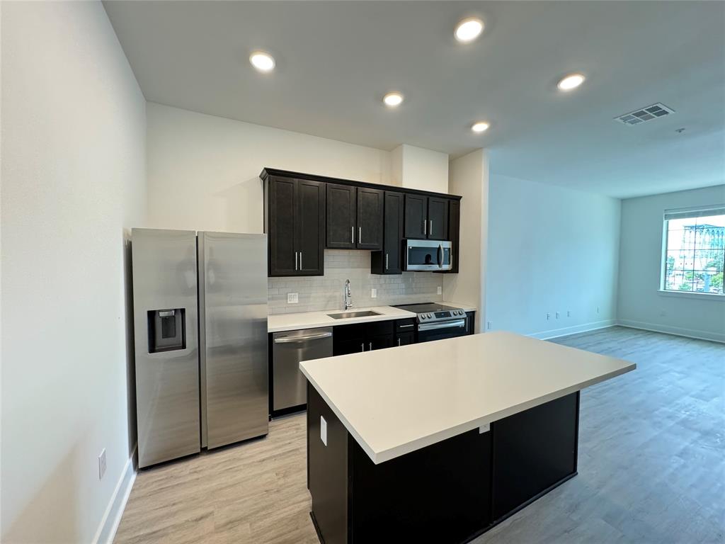 a kitchen with stainless steel appliances a refrigerator sink and microwave