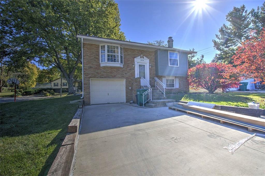 a view of a house with a yard and a large tree