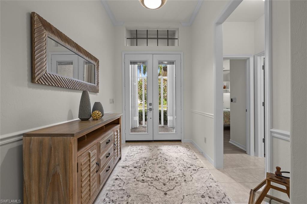 Entryway featuring light tile patterned floors, french doors, and crown molding