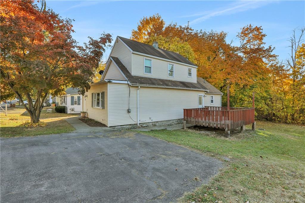 Back of house with a deck and a lawn