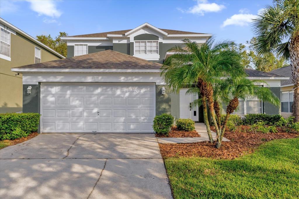 a view of a brick house with a small yard plants and palm trees