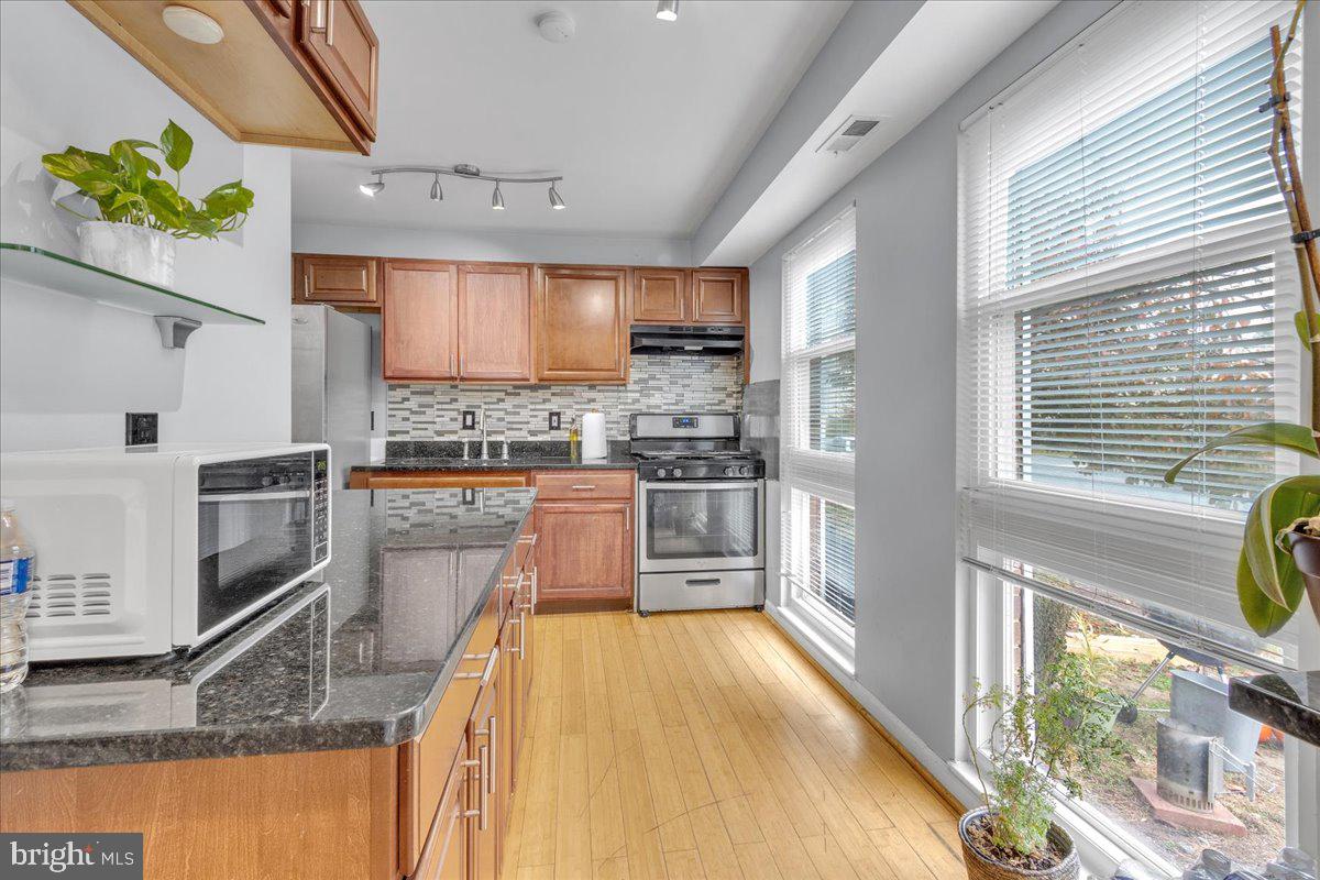 a kitchen with stainless steel appliances kitchen island granite countertop a stove a sink and a microwave