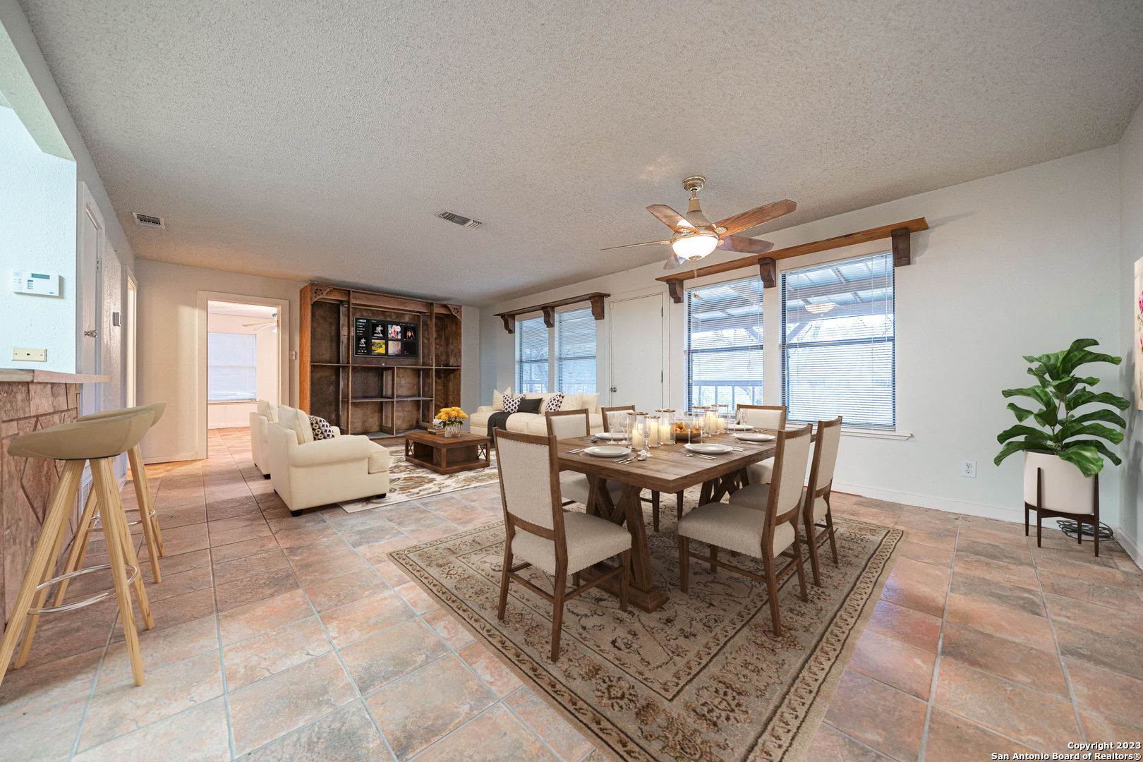 a living room with furniture a dining table and a potted plant