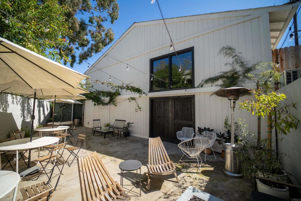 a view of a patio with table and chairs potted plants and floor to ceiling window