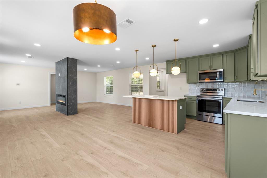 a large kitchen with a large counter top stainless steel appliances and cabinets